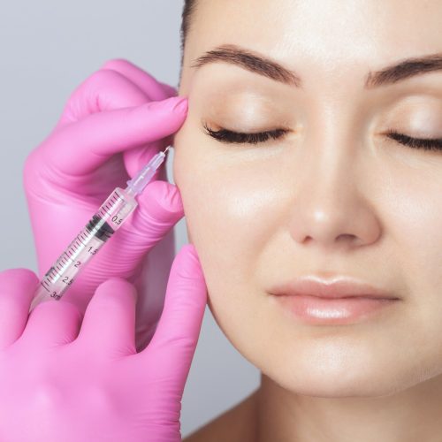 The doctor cosmetologist makes the Rejuvenating facial injections procedure for tightening and smoothing wrinkles on the face skin of a beautiful woman in a beauty salon.Cosmetology skin care.